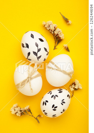 Easter background - white easter egg with flowers inside on yellow background. Happy easter, spring, summer floral concept Easter background - white easter egg with flowers inside on yellow background. Happy easter, spring, summer floral concept 126244694