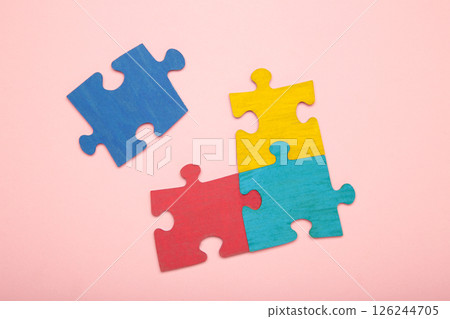 Colorful puzzle on pink background. Multi-colored heart as a symbol of World Autism Awareness Day. Top view Colorful puzzle on pink background. Multi-colored heart as a symbol of World Autism Awareness Day. Top view 126244705