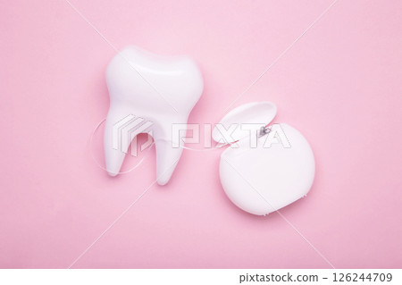 White healthy tooth with dental floss on pink. Oral dental care products, hygiene cleaning personal use lifestyle concept White healthy tooth with dental floss on pink. Oral dental care products, hygiene cleaning personal use lifestyle concept 126244709