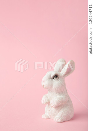 White ceramic rabbit on pink background. Vertical photo 126244711
