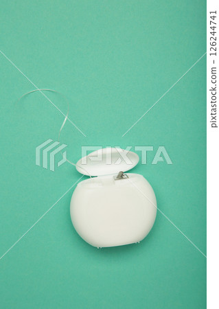 Dental floss on mint background. Vertical photo 126244741