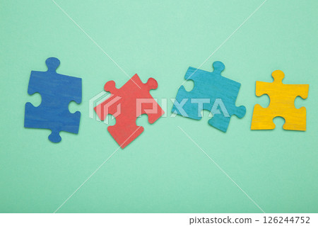 Colorful puzzle on mint background. Multi-colored heart as a symbol of World Autism Awareness Day. Top view Colorful puzzle on mint background. Multi-colored heart as a symbol of World Autism Awareness Day. Top view 126244752