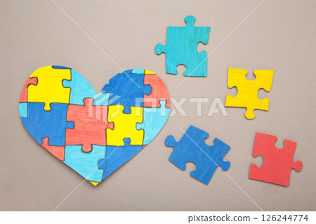 Colorful puzzle heart on grey background. Multi-colored heart as a symbol of World Autism Awareness Day. Top view Colorful puzzle heart on grey background. Multi-colored heart as a symbol of World Autism Awareness Day. Top view 126244774