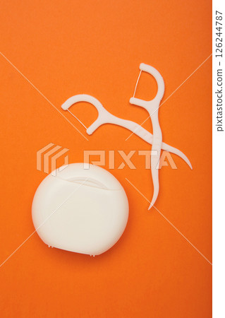 Floss toothpick on orange background. Dental hygiene concept. Vertical photo 126244787