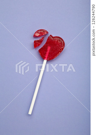 Broken heart lollipop on purple background. Vertical photo 126244790