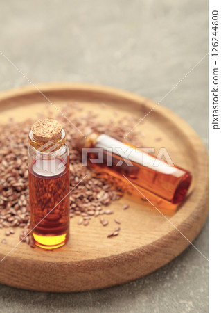 Flaxseeds with flaxseed oil in glass bottle on grey concrete background. Vertical photo 126244800
