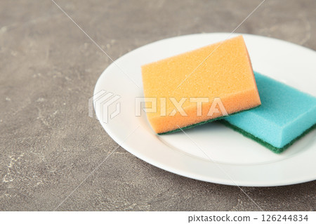 Cleaning sponge with plate on grey concrete background. top view Cleaning sponge with plate on grey concrete background. top view 126244834