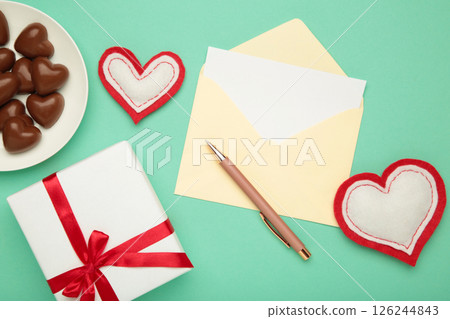 Valentine's day greeting card with gift, hearts chocolate sweets and letter on mint background. 126244843