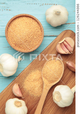 Fresh garlic and garlic powder in bowl on blue background. Using spices for meals. Top view 126244866