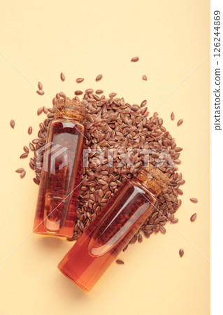Flaxseeds with flaxseed oil in glass bottle on beige background. Flaxseeds with flaxseed oil in glass bottle on beige background. 126244869