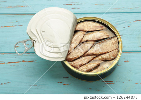 Opened can with sprats in oil on a wooden blue background 126244873