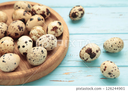 Quail eggs in wooden plate on blue wooden background 126244901