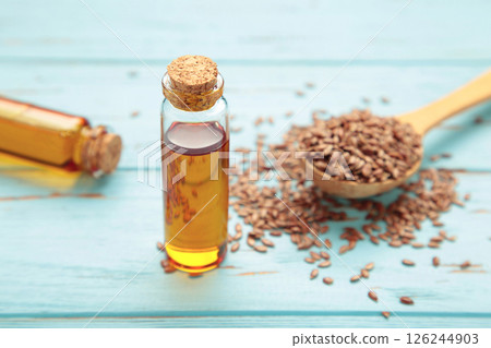 Flaxseeds with flaxseed oil in glass bottle on blue wooden background. 126244903