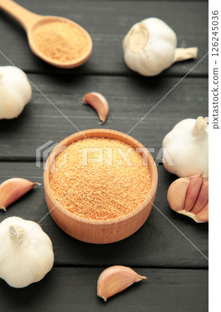 Fresh garlic and garlic powder on black wooden background. Using spices for meals. Top view 126245036