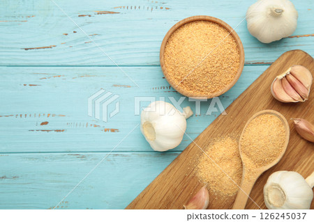 Fresh garlic and garlic powder on blue wooden background. Using spices for meals. Top view 126245037