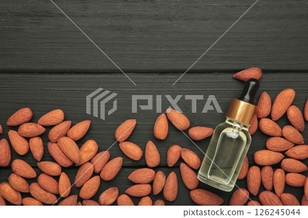Fresh almond oil with almond nuts on black wooden background. Vertical photo 126245044