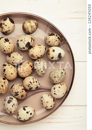 Quail eggs in plate on white wooden background. Vertical photo Quail eggs in plate on white wooden background. Vertical photo 126245050