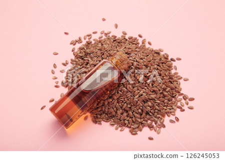 Flaxseeds with flaxseed oil in glass bottle on pink background. 126245053