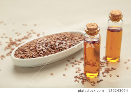 Flaxseeds with flaxseed oil in glass bottle on light background. 126245054