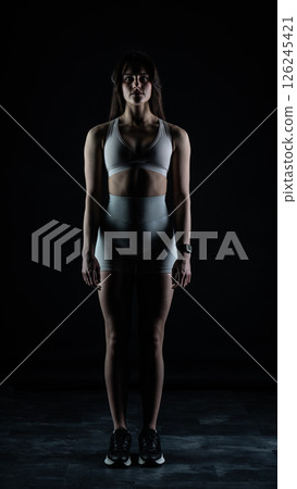 Young beautiful woman with athletic body on dark background. Fitness girl Young beautiful woman with athletic body on dark background. Fitness girl 126245421