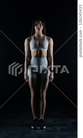 Young beautiful woman with athletic body on dark background. Fitness girl 126245433