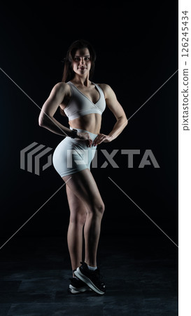 Young beautiful woman with athletic body on dark background. Fitness girl 126245434