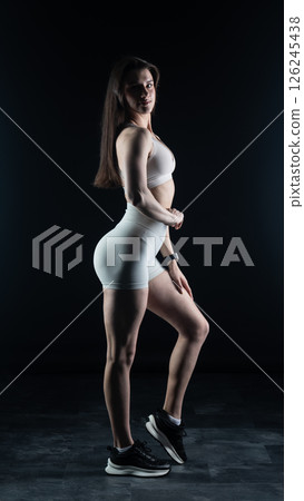 Young beautiful woman with athletic body on dark background. Fitness girl Young beautiful woman with athletic body on dark background. Fitness girl 126245438