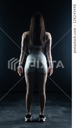 Young beautiful woman with athletic body on dark background. Fitness girl Young beautiful woman with athletic body on dark background. Fitness girl 126245448