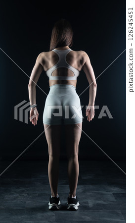 Young beautiful woman with athletic body on dark background. Fitness girl Young beautiful woman with athletic body on dark background. Fitness girl 126245451