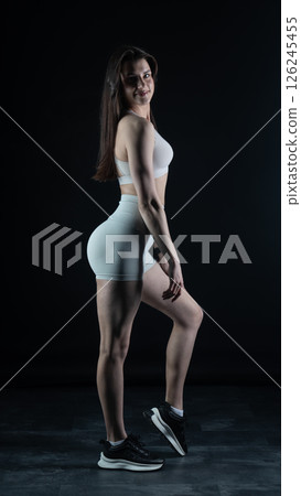 Young beautiful woman with athletic body on dark background. Fitness girl 126245455