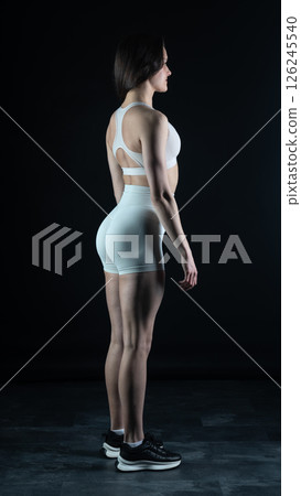 Young beautiful woman with athletic body on dark background. Fitness girl Young beautiful woman with athletic body on dark background. Fitness girl 126245540