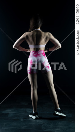 Young beautiful fitness woman on a black background. Fitness girl, female bodybuilder on a dark background 126245640