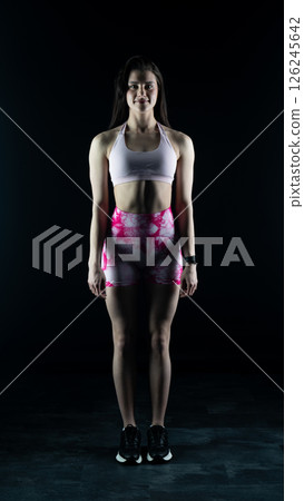 Young beautiful fitness woman on a black background. Fitness girl, female bodybuilder on a dark background 126245642