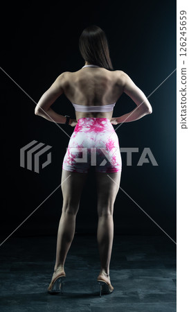 Young beautiful fitness woman on a black background. Fitness girl, female bodybuilder on a dark background 126245659