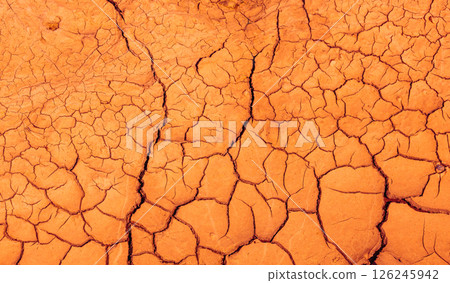 Cracked Earth. An arid landscape with cracked, dry earth patterns in a warm orange hue Cracked Earth. An arid landscape with cracked, dry earth patterns in a warm orange hue 126245942