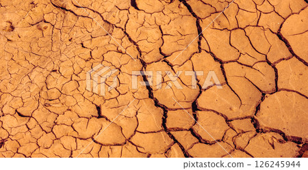 Cracked Earth. An arid landscape with cracked, dry earth patterns in a warm orange hue 126245944