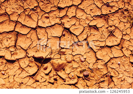 Cracked Earth. An arid landscape with cracked, dry earth patterns in a warm orange hue Cracked Earth. An arid landscape with cracked, dry earth patterns in a warm orange hue 126245953