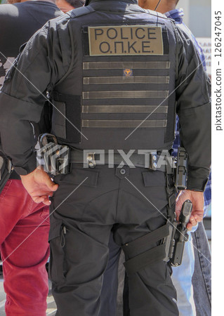 Greece, Thessaloniki, police officer seen from behind with his hand on his weapon Greece, Thessaloniki, police officer seen from behind with his hand on his weapon 126247045