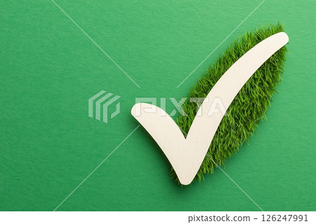 White check mark symbol over green grass and green background representing sustainability 126247991
