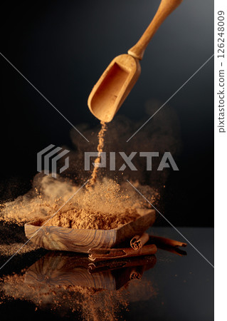 Cinnamon powder is poured into a wooden dish. Cinnamon powder is poured into a wooden dish. 126248009