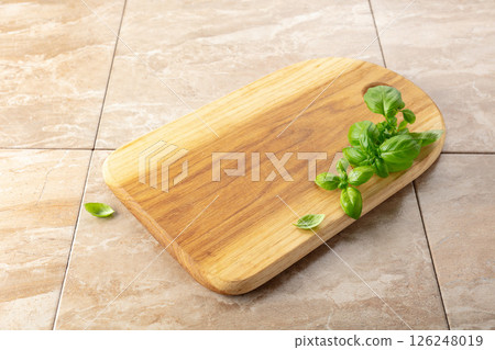 Cutting board and basil on a kitchen table. 126248019