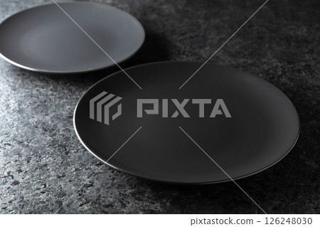 Black ceramic plates on a black stone table. Black ceramic plates on a black stone table. 126248030