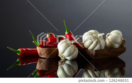 Garlic bulbs and red chili peppers on a black background. Garlic bulbs and red chili peppers on a black background. 126248031