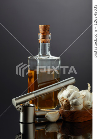 Garlic bulbs, garlic press, and bottle of vegetable oil. Garlic bulbs, garlic press, and bottle of vegetable oil. 126248035