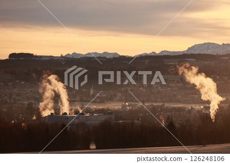 The smoke from a factory is rising into the sky, creating a hazy atmosphere The smoke from a factory is rising into the sky, creating a hazy atmosphere 126248106