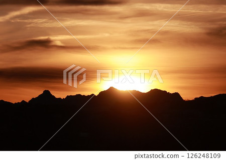The sun is setting behind a mountain range 126248109