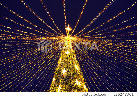 Christmas tree with garland lights in the city center of city at winter night. Golden Christmas tree in the city center. 126248301