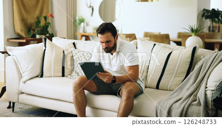 Home, typing and man on sofa, tablet and internet with online reading, serious and investment. Apartment, tech and person on couch, connection and tax report with digital app for savings and trading Home, typing and man on sofa, tablet and internet with online reading, serious and investment. Apartment, tech and person on couch, connection and tax report with digital app for savings and trading 126248733