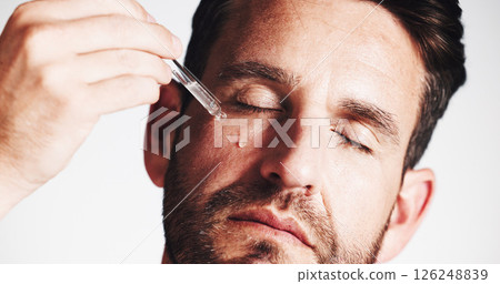 Serum, beauty and glow with man in studio for skincare treatment, anti aging benefits and hydration. Collagen, shine and oil dropper with mature person on white background for cosmetics and self care Serum, beauty and glow with man in studio for skincare treatment, anti aging benefits and hydration. Collagen, shine and oil dropper with mature person on white background for cosmetics and self care 126248839