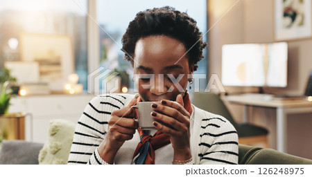 Black woman, relax and coffee aroma in home to start morning, warm scent and caffeine satisfaction. Smile, person and smell hot beverage on sofa with nostalgia, thinking or weekend break in apartment 126248975